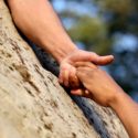 Kalliolta alaspäin kurottava käsi auttaa toista ihmistä kallion päälle
